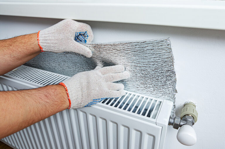 Installing reflective foil behind a radiator to avoid heat loss into the wall